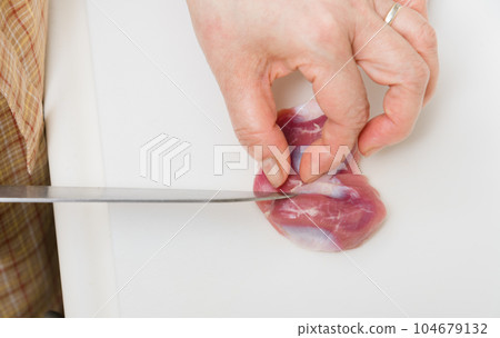 [Housewife preparing yakitori gizzards with a knife] 104679132