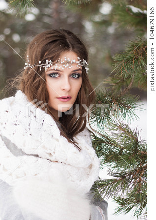 Beautiful bride in a white dress with a bouquet in a snow-covered winter forest. Portrait of the bride in nature 104679166