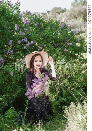 A fashionable girl with dark hair, a spring portrait in lilac tones in summer. Bright professional makeup. A fashionable girl with dark hair, a spring portrait in lilac tones in summer. Bright professional makeup. 104679463