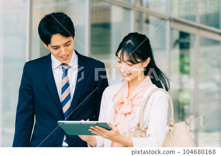 男性和女性辦公室職員在商務中查看平板電腦 104680168
