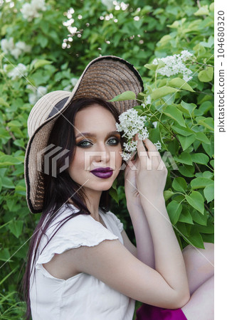 A fashionable girl with dark hair, a spring portrait in lilac tones in summer. Bright professional makeup. A fashionable girl with dark hair, a spring portrait in lilac tones in summer. Bright professional makeup. 104680320