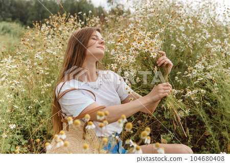 Beautiful young woman in nature with a bouquet of daisies. Field daisies, field of flowers. Beautiful young woman in nature with a bouquet of daisies. Field daisies, field of flowers. 104680408