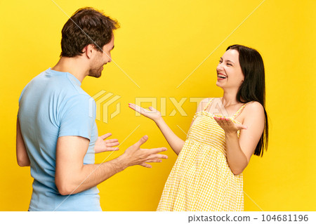 Big surprise and happiness. Young woman emotionally talking to her husband, expressing joy against yellow studio background Big surprise and happiness. Young woman emotionally talking to her husband, expressing joy against yellow studio background 104681196