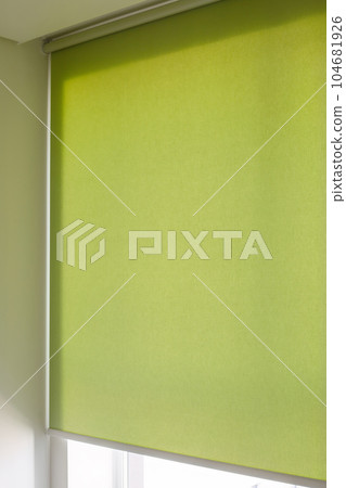 Roller blinds automatic close-up on the window. Selective focus. Motorized shades. Green color curtain, texture fabric. City outside the window. 104681926