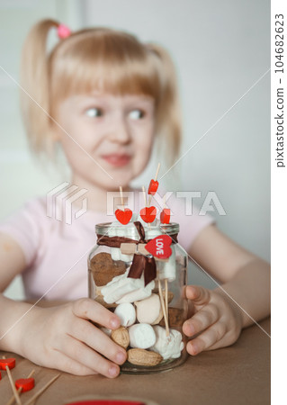 A little girl blogger makes a sweet Valentine's Day gift with her own hands. A gift for the holiday, a video blog entry. 104682623