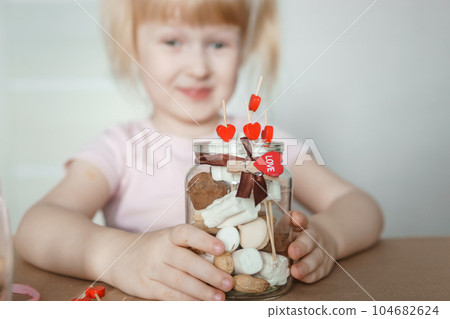 A little girl blogger makes a sweet Valentine's Day gift with her own hands. A gift for the holiday, a video blog entry. 104682624