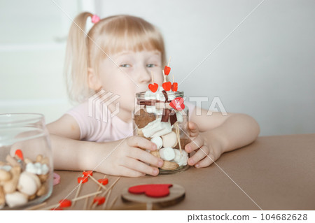 A little girl blogger makes a sweet Valentine's Day gift with her own hands. A gift for the holiday, a video blog entry. 104682628