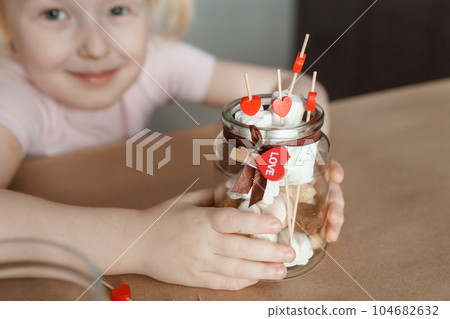 A little girl blogger makes a sweet Valentine's Day gift with her own hands. A gift for the holiday, a video blog entry. 104682632