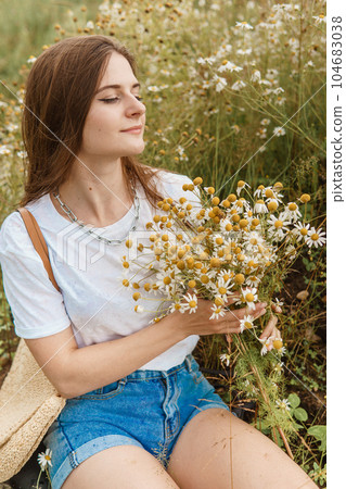 Beautiful young woman in nature with a bouquet of daisies. Field daisies, field of flowers. Beautiful young woman in nature with a bouquet of daisies. Field daisies, field of flowers. 104683038