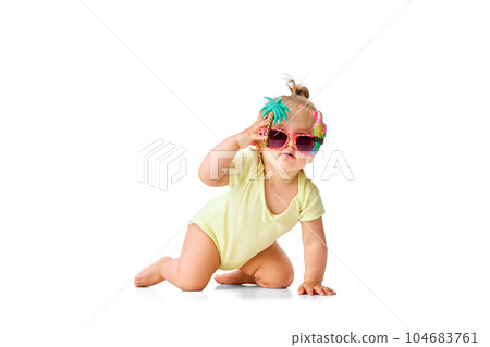 Summer chill. Stylish, positive little girl, toddler in yellow costume and funny sunglasses crawling on floor against white studio background 104683761