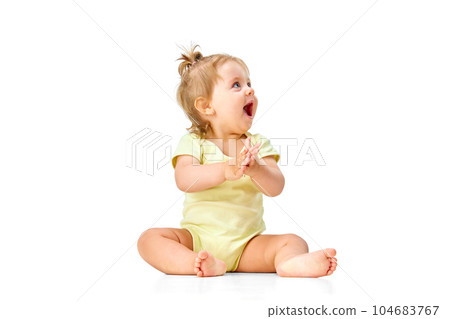 Joyful, happy little baby girl, child sitting on floor, capping hands and laughing against white studio background Joyful, happy little baby girl, child sitting on floor, capping hands and laughing against white studio background 104683767
