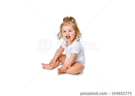 Happy, smiling child. Little baby girl, toddler sitting on floor and cheerfully laughing against white studio background 104683775