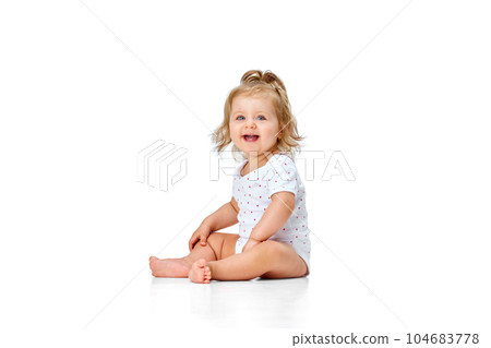 Beautiful, happy, smiling child. Little baby girl, toddler sitting on floor with joy and fun against white studio background 104683778