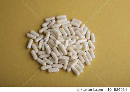 White Medicine Capsules On Orange 104684934