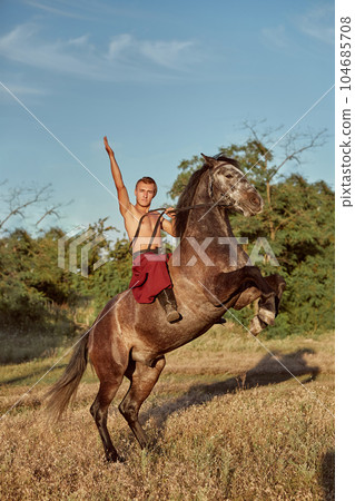 Handsome man cowboy riding on a horse - background of sky and trees 104685708