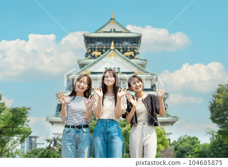 A woman visiting Osaka Castle on a trip with her friends 104685875