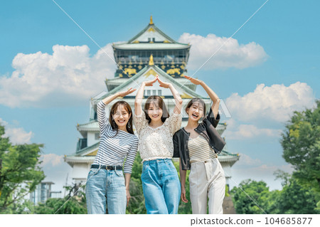 A woman visiting Osaka Castle on a trip with her friends 104685877
