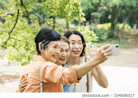 Middle-aged woman taking a picture with a smartphone with her friend 104686027