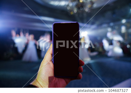 Women's hands with a smartphone take photos or videos of performances. Women's hands with a smartphone take photos or videos of performances. 104687327