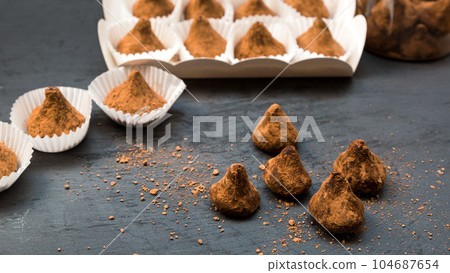 Sugar scrubs in the form of truffles in separate portion substrates for sweets on a black background Sugar scrubs in the form of truffles in separate portion substrates for sweets on a black background 104687654