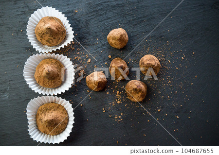 Sugar scrubs in the form of truffles in separate portion substrates for sweets on a black background Sugar scrubs in the form of truffles in separate portion substrates for sweets on a black background 104687655