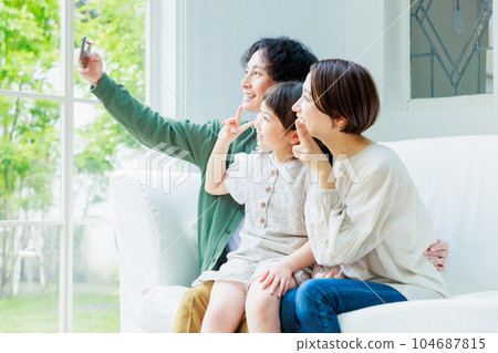 Family sitting on the sofa in the living room and taking a selfie 104687815