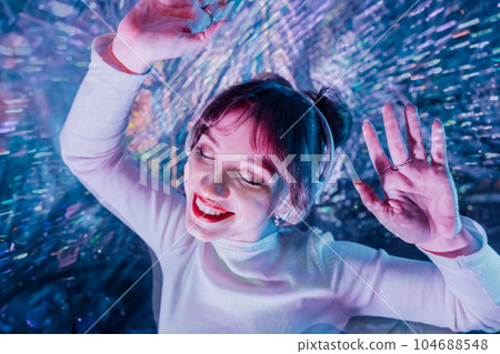happy smiling woman with closed eyes and raised hands in white clothes and headphones dancing. Music lover. White dress code party, silent disco. Enjoy moment on shiny background. Selective focus happy smiling woman with closed eyes and raised hands in white clothes and headphones dancing. Music lover. White dress code party, silent disco. Enjoy moment on shiny background. Selective focus 104688548