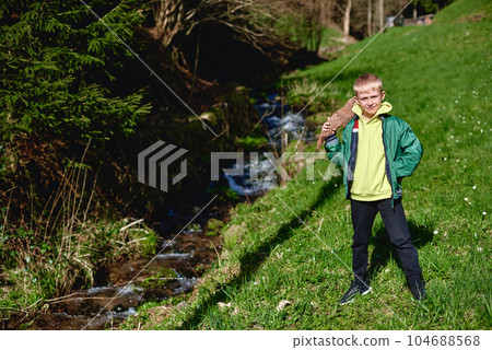 A little boy walks along a mountain river. Through the clear water, he examines the pebbles at the bottom of the river 104688568