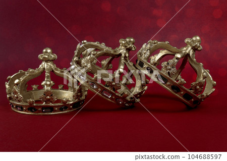 Three gold crowns on red background. Concept for Reyes Magos, Three Wise Men or Happy Epiphany day. Three gold crowns on red background. Concept for Reyes Magos, Three Wise Men or Happy Epiphany day. 104688597