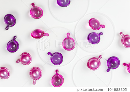 Pink and purple capsule with cosmetic oil for face isolated on a white background. Pink and purple capsule with cosmetic oil for face isolated on a white background. 104688805