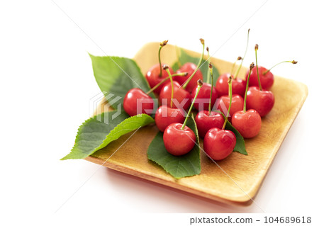初夏水果櫻桃，葉子放在白色背景的木方盤上 104689618