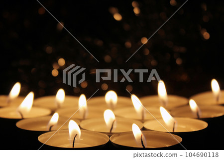 White Candles Burning in the Dark with focus on two candles in foreground. 104690118