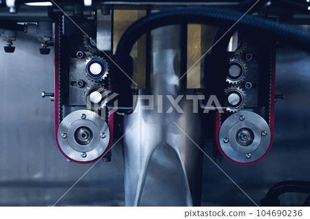 Elements of the production mechanism. Metal gears and rotation transmission belts. Toned industrial image with selective focus Elements of the production mechanism. Metal gears and rotation transmission belts. Toned industrial image with selective focus 104690236
