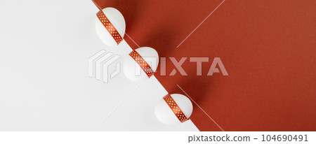 Easter banner. White Easter decorated eggs on orange and white paper background. Easter banner. White Easter decorated eggs on orange and white paper background. 104690491