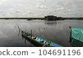 A view of a wooden boat belonging to a local resident leaning on a riverside pier with a cloudy sky in the background 104691196