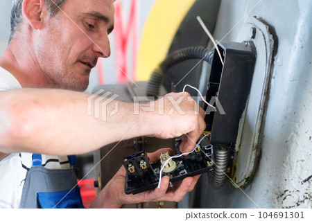Professional electrician repairs industrial equipment in production workshop. Diagnostics of power 104691301