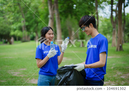 Multiethnic volunteers donate their time holding black garbage bags to collect plastic waste for recycling to reduce pollution in a public park Multiethnic volunteers donate their time holding black garbage bags to collect plastic waste for recycling to reduce pollution in a public park 104691302