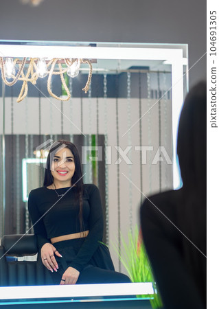 Portrait of beautiful young Asian woman in reflection of mirror in beauty salon. Back view. Charming Portrait of beautiful young Asian woman in reflection of mirror in beauty salon. Back view. Charming 104691305