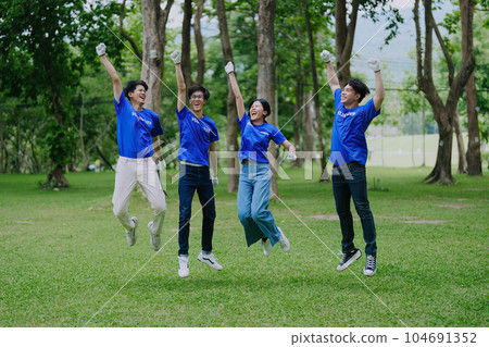 Volunteers of various nationalities are showing solidarity, donating their personal time, holding black trash bags to collect plastic waste for recycling to reduce pollution in a public park Volunteers of various nationalities are showing solidarity, donating their personal time, holding black trash bags to collect plastic waste for recycling to reduce pollution in a public park 104691352