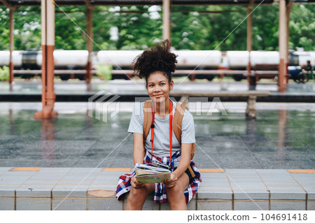 Asian teenage girl african american traveler dressed in casual wear holding map and searching right direction of route 104691418