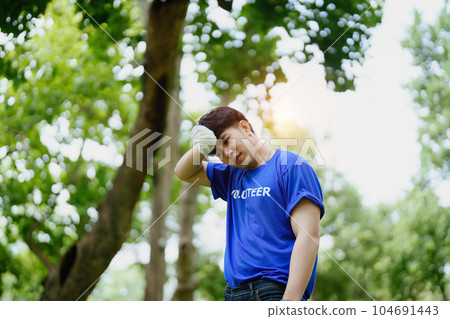 Multiethnic volunteers donate their time holding black garbage bags to collect plastic waste for recycling to reduce pollution in a public park 104691443