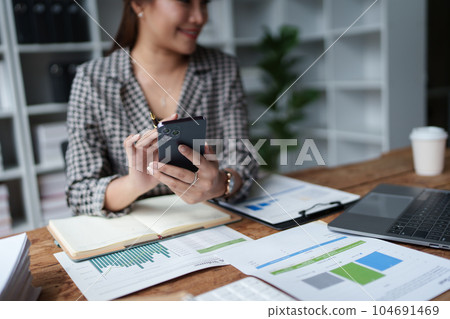 Consultant, Asian businesswoman working on the phone who discussion financial work and marketing business plan to increase company profits, ready to use computer and marketing planning documents. Consultant, Asian businesswoman working on the phone who discussion financial work and marketing business plan to increase company profits, ready to use computer and marketing planning documents. 104691469