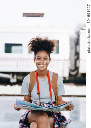 Asian teenage girl african american traveler dressed in casual wear holding map and searching right direction of route 104691627