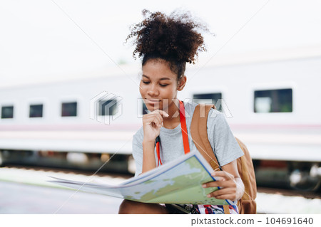 Asian teenage girl african american traveler dressed in casual wear holding map and searching right direction of route Asian teenage girl african american traveler dressed in casual wear holding map and searching right direction of route 104691640