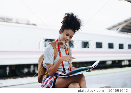 Asian teenage girl african american traveler dressed in casual wear holding map and searching right direction of route Asian teenage girl african american traveler dressed in casual wear holding map and searching right direction of route 104691642