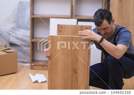Custom furniture delivery and installation concentrated handyman checking planks made of quality hardwood ready to assemble rack for office interior carpentry industry Custom furniture delivery and installation concentrated handyman checking planks made of quality hardwood ready to assemble rack for office interior carpentry industry 104692198