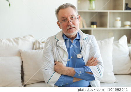 Mature senior male doctor in glasses medical uniform smiling looking at camera in hospital. General practitioner GP therapist professional healthcare expert in clinic. Healthcare concept Mature senior male doctor in glasses medical uniform smiling looking at camera in hospital. General practitioner GP therapist professional healthcare expert in clinic. Healthcare concept 104692941