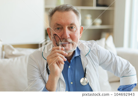 Mature senior male doctor in glasses medical uniform smiling looking at camera in hospital. General practitioner GP therapist professional healthcare expert in clinic. Healthcare concept Mature senior male doctor in glasses medical uniform smiling looking at camera in hospital. General practitioner GP therapist professional healthcare expert in clinic. Healthcare concept 104692943