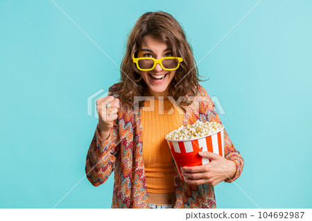 Woman in 3D glasses eating popcorn and watching interesting tv serial, sport game film, online movie Woman in 3D glasses eating popcorn and watching interesting tv serial, sport game film, online movie 104692987