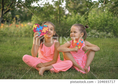 The kid proudly holds a heart-shaped card with a picture of colored puzzles - a symbol of awareness about autism. Worldwide support for special children The kid proudly holds a heart-shaped card with a picture of colored puzzles - a symbol of awareness about autism. Worldwide support for special children 104693717